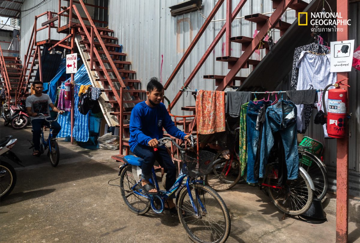 ผู้ชาย ขี่จักรยาน ในแคมป์ ที่พักของคนงานก่อสร้าง